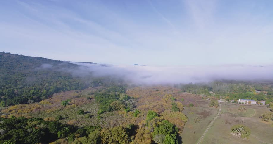 Aerial panorama of a landscape with mountains trees and mist