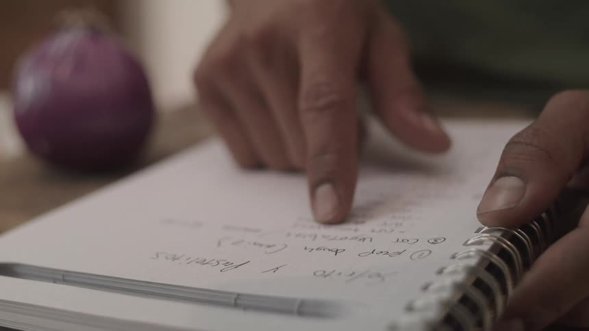 Closeup of a mans hands reading a notebook and moving his index finger