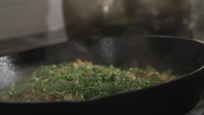 Skillet cooking a dough with ingredients and being stirred by a hand