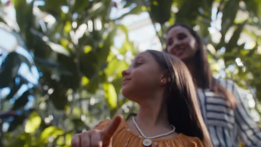 Mother behind her daughter who has a butterfly on the tips of her fingers