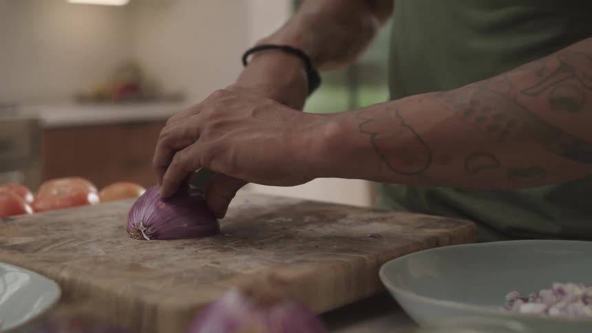 Closeup of a mans hands cutting a red onion