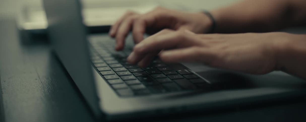 Worker types on laptop keyboard using only two fingers on each hand