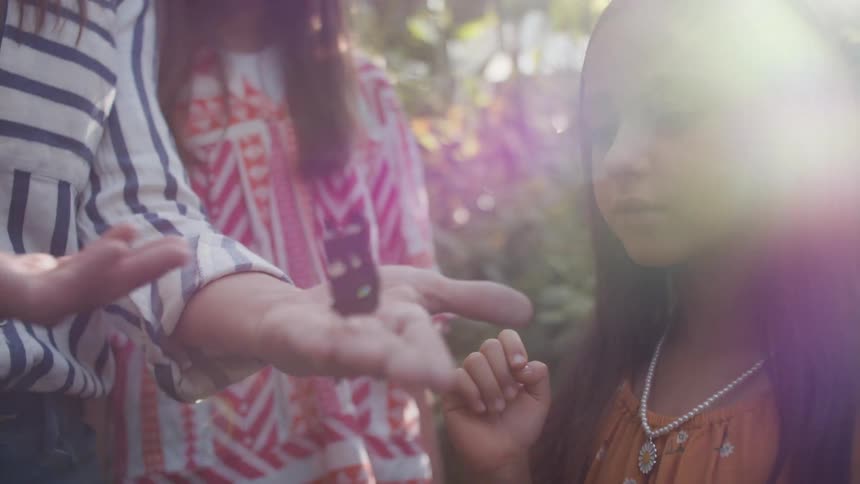 Girl observing a butterfly in her mothers hands
