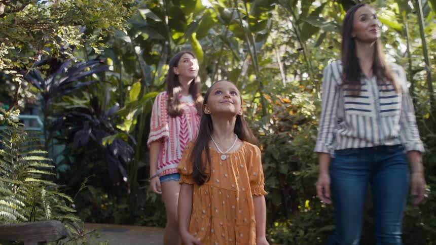 Mother with her two daughters inside a greenhouse with plants