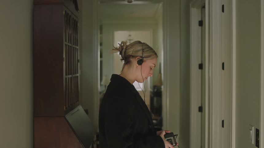 A clip of a white lady on a black coat putting on her headset