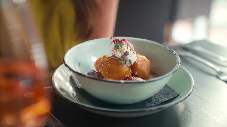 A human hand placing a bowl of food on a table
