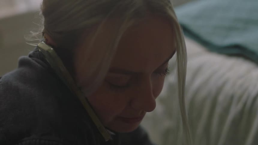 A blonde woman with a cell phone to her ear talks while doing actions with her arms