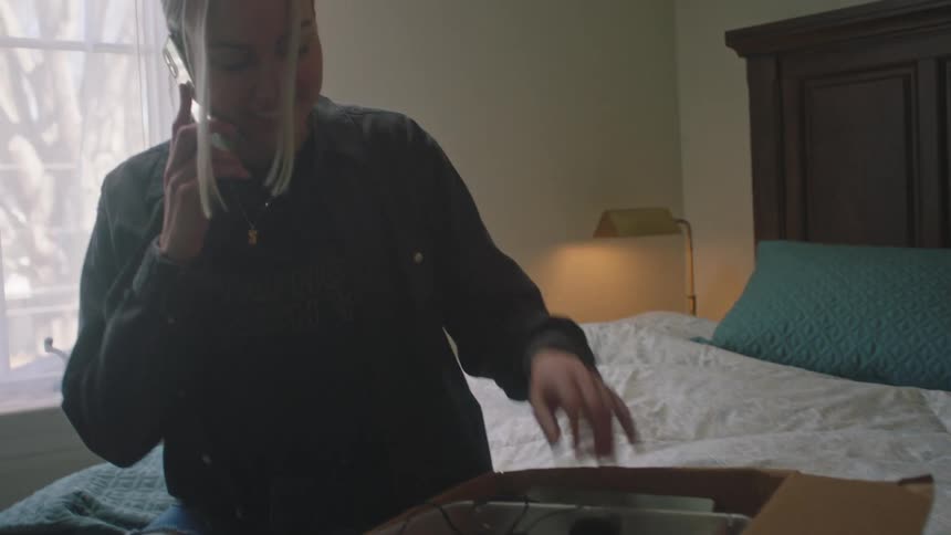 Woman talking on the phone finds old belongings under the bed