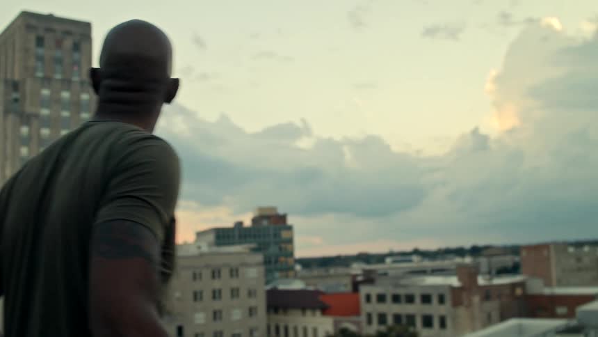 Man looks at the city from a balcony