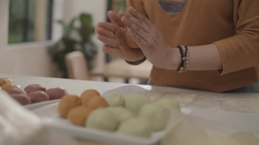 Hands of a person rolling colorful sweet dough