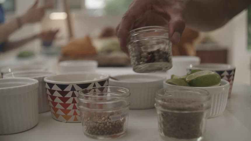 Closeup of spices in jars and hands of a person picking them up
