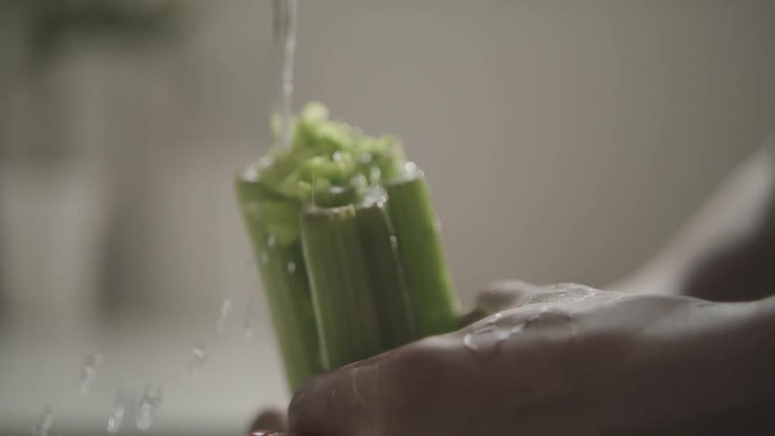 Closeup of a womans hands washing vegetables under the faucet