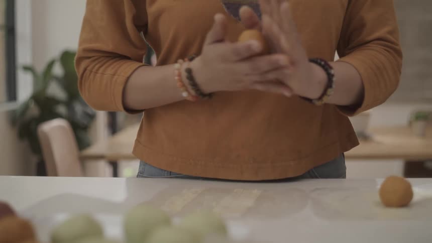 View of trays with food balls and a woman preparing one