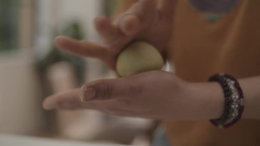 Closeup of hands making circular motions with dough
