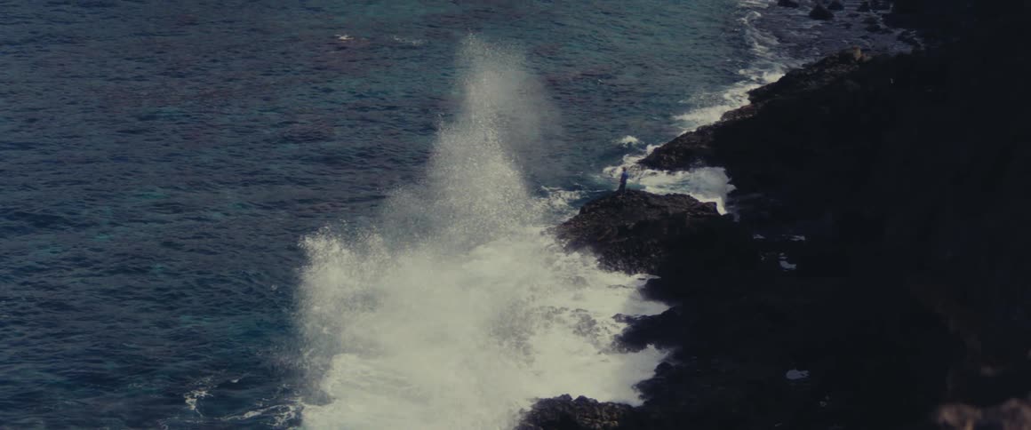 Waves roll into shore and splash against rocks along the coast