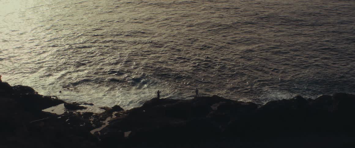 Two people on the sea coast admiring the landscape during sunset