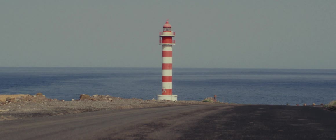 A striped lighthouse is on the shore