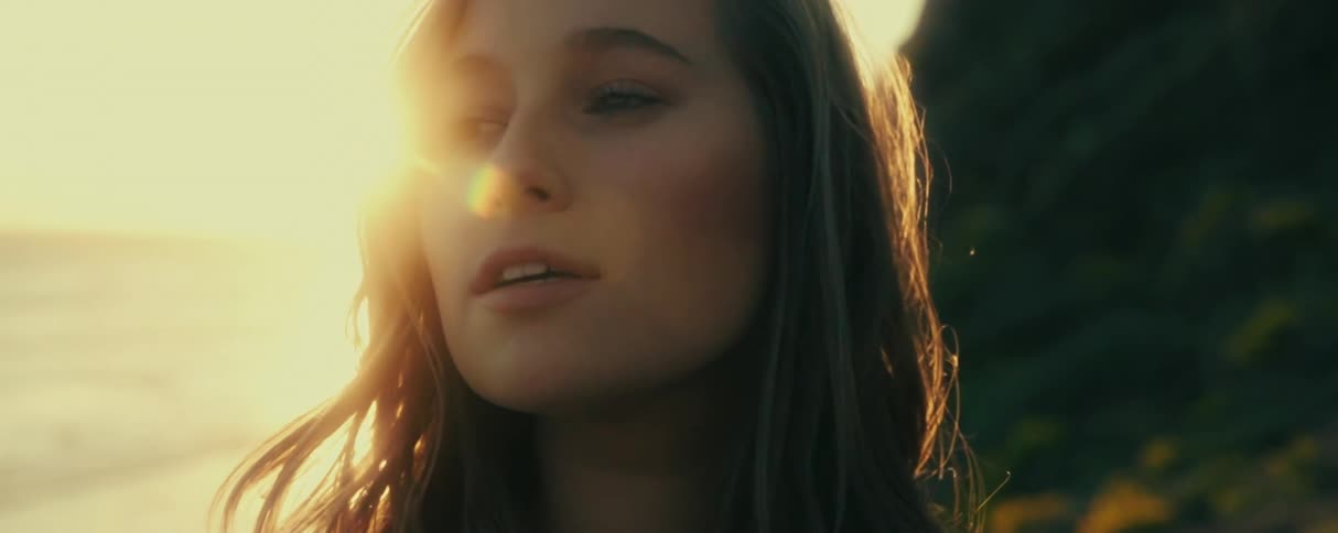 Portrait of a young woman smelling a yellow flower by the seaside