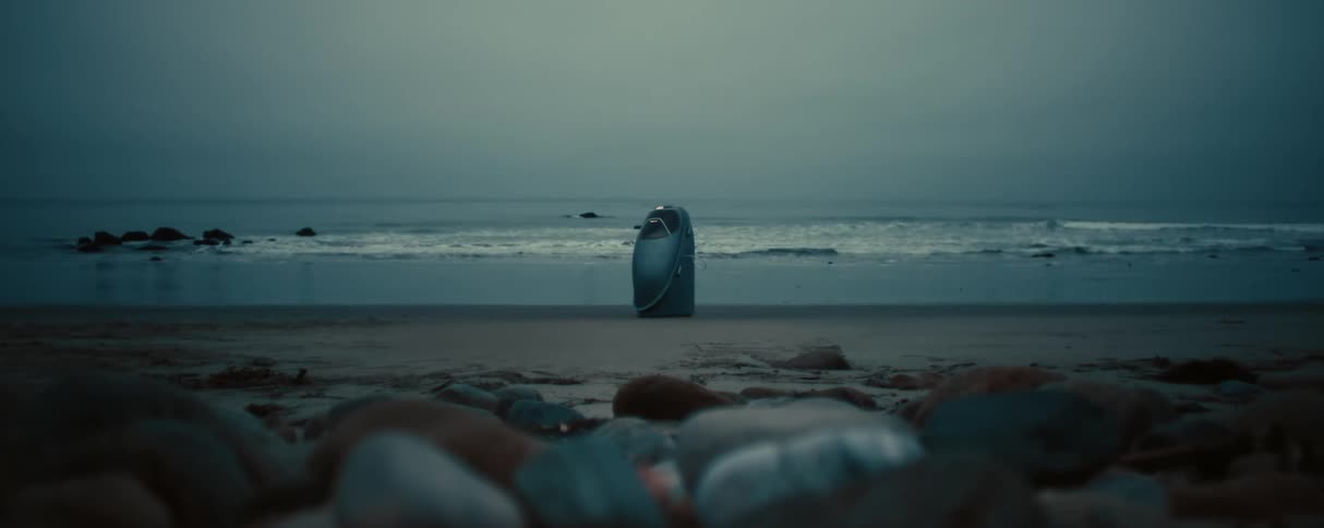 Robot sits at the waterline of a rockfilled beach