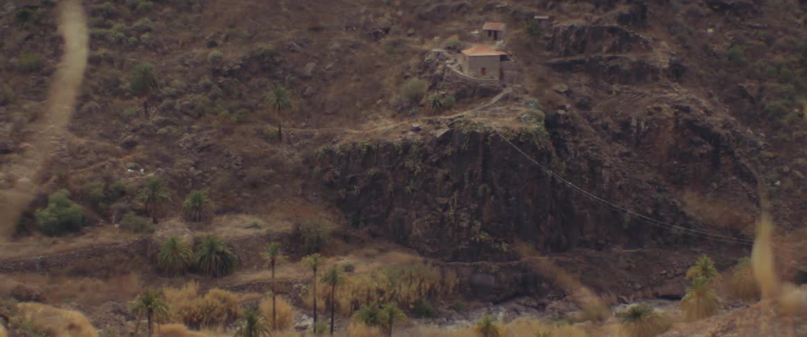 House sits on slope ending in cliff overlooking narrow valley