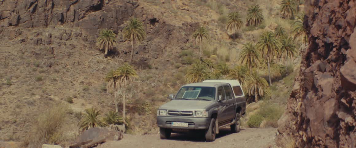 Pickup truck on a dirt road amidst mountains