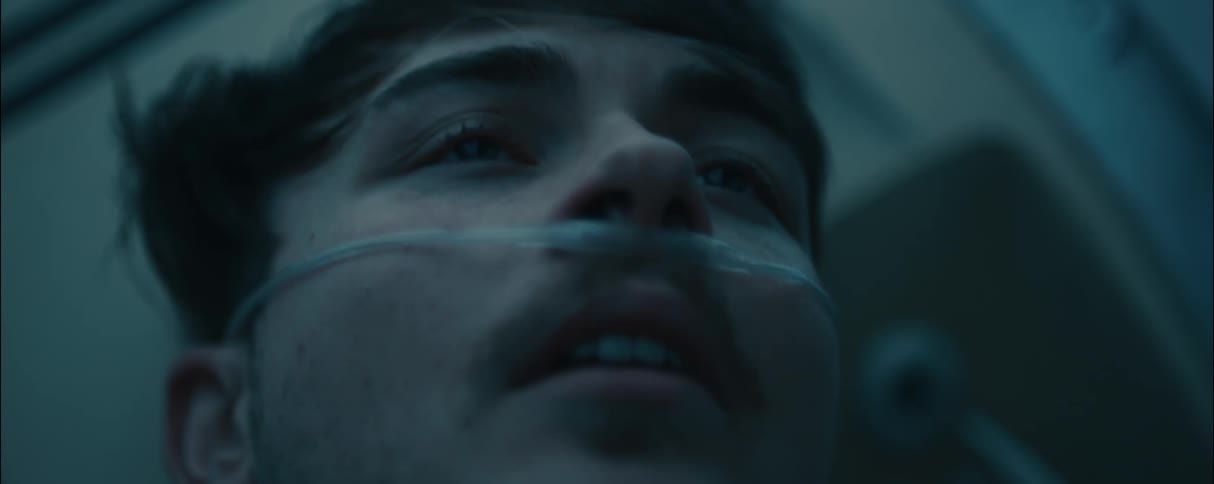 A young man is lying down with a respirator in his nose