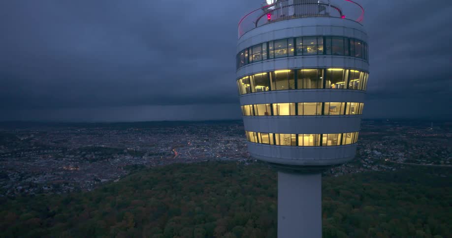 An observatory towers above a city in the distance on a cloudy evening