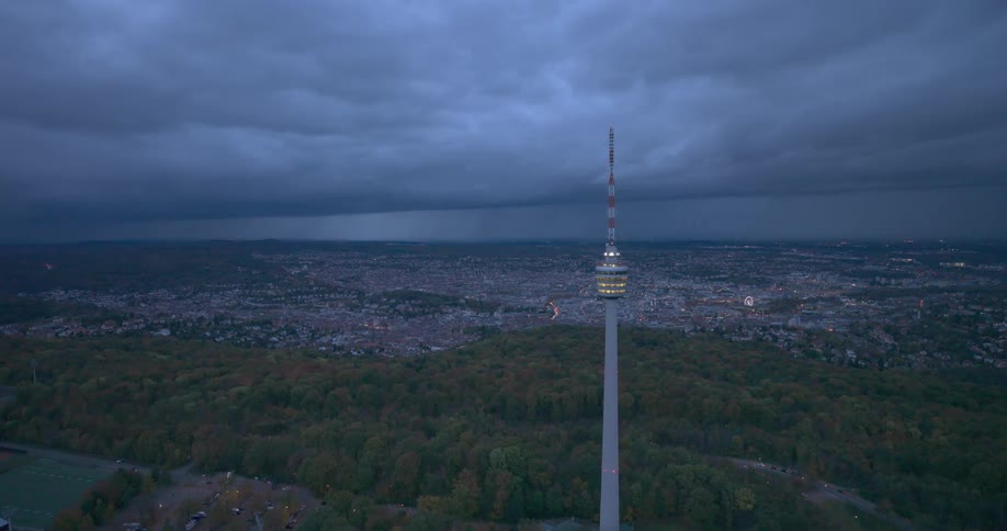 Flashing light on the stuttgart tower with forest and city in the background at night