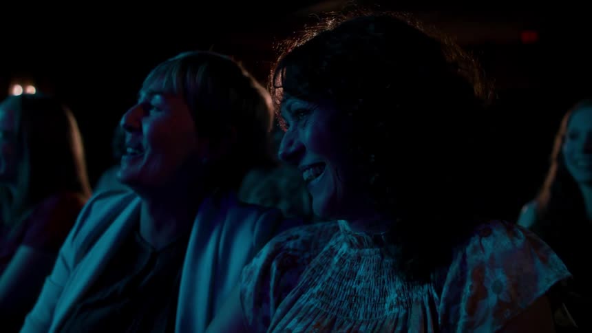 Two friends laugh while watching a movie