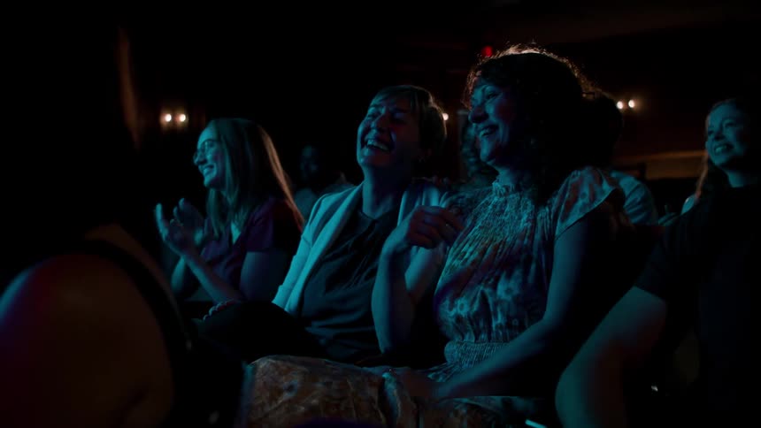 People sitting in an auditorium smiling and applauding