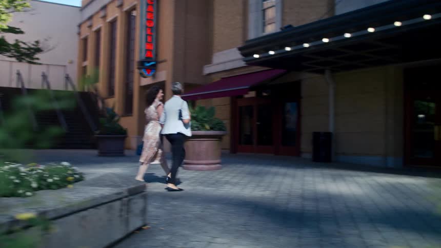 Two people walking towards a commercial establishment in the city