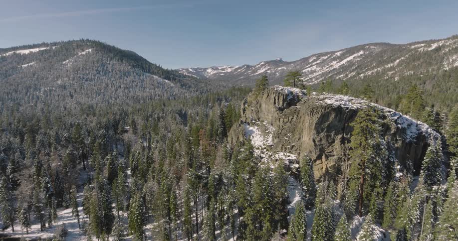 Aerial of hills and an evergreen forest on a sunny winter day