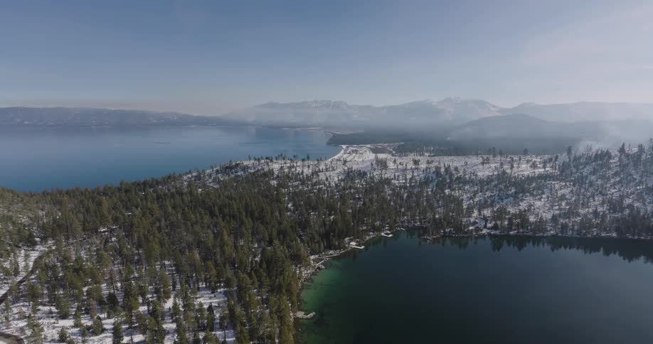 Aerial panorama of a mountain range with coniferous trees and snow by the sea