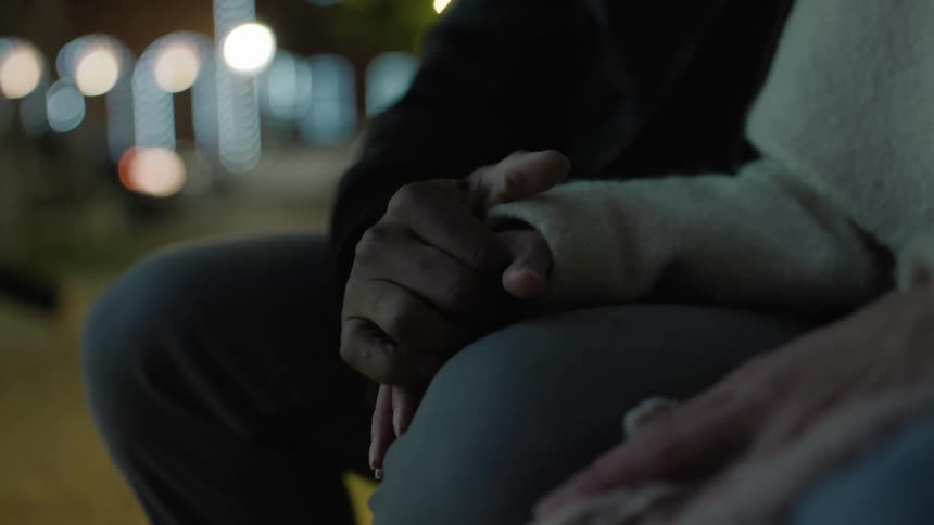 A man and woman sit and hold hands
