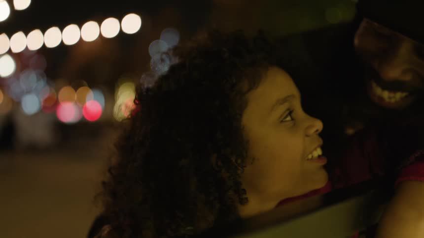 A father and daughter laugh at something at night
