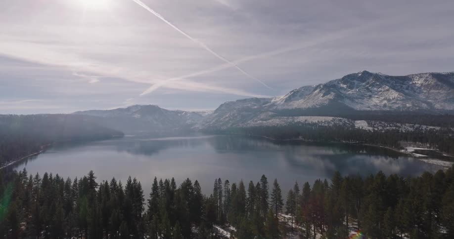 Aerial of lake tahoe surrounded by forest and snowy mountains