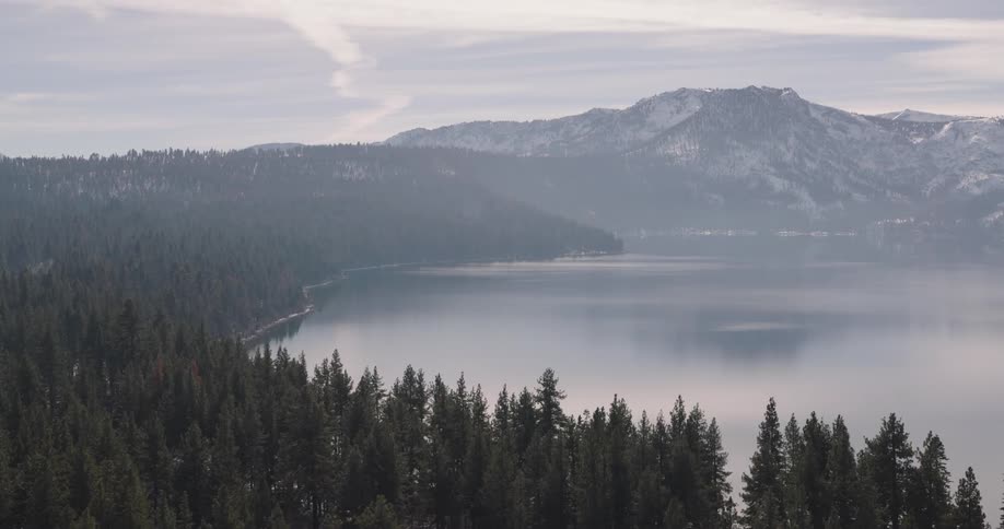 Aerial panorama of forests and snowcovered mountains with a central lake