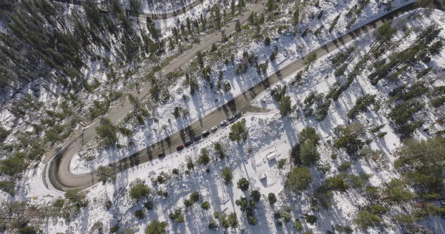 Aerial panorama of a road amidst snowy mountains and trees