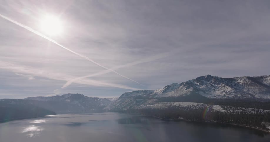 Aerial of a frozen lake surrounded by mountains and forest