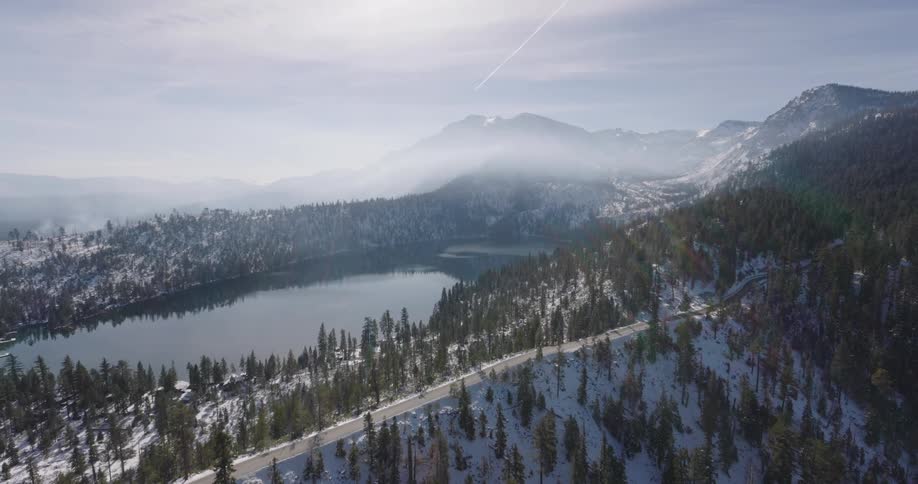 A lake is surrounded by mountains that are covered in snow and trees