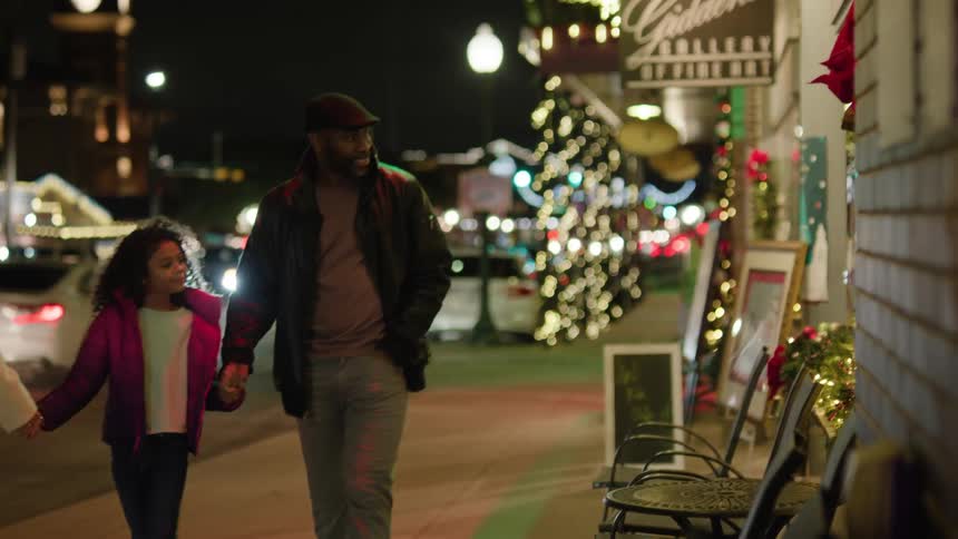 A family walk past the holiday decorations on the shops