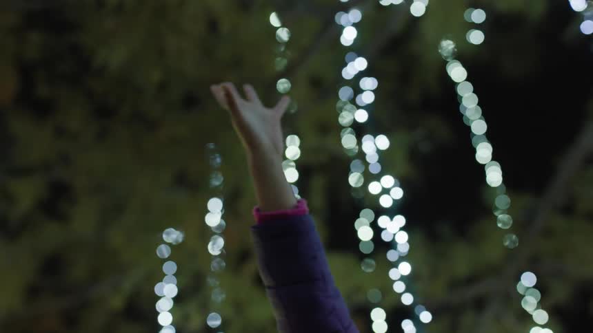 A child reaches up to the lighted decorations