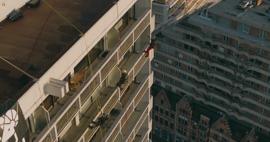 People are descending the building on ropes