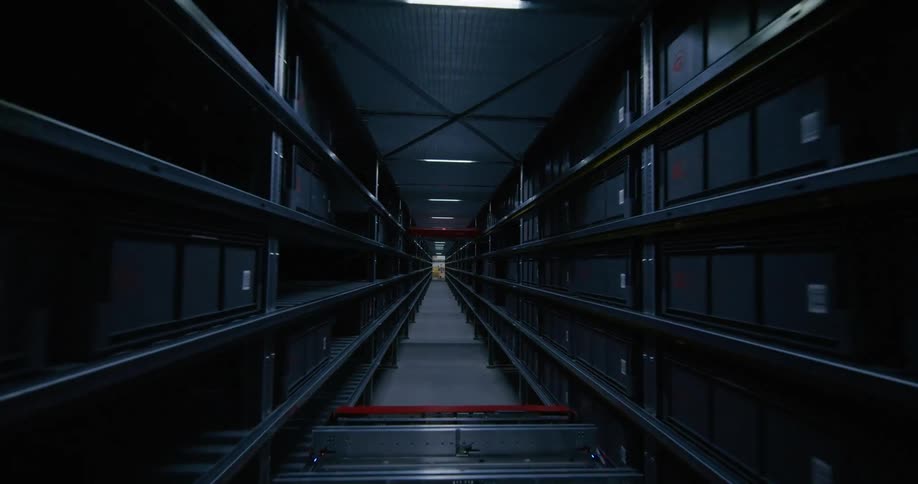 The camera passes through a warehouse full of countless shelves