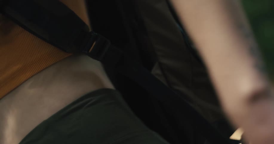 Closeup of a womans hands adjusting the strap of a black backpack