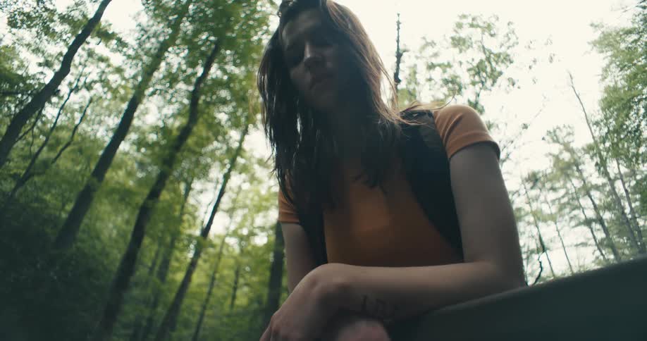 Sad woman reclined on a fence in the forest