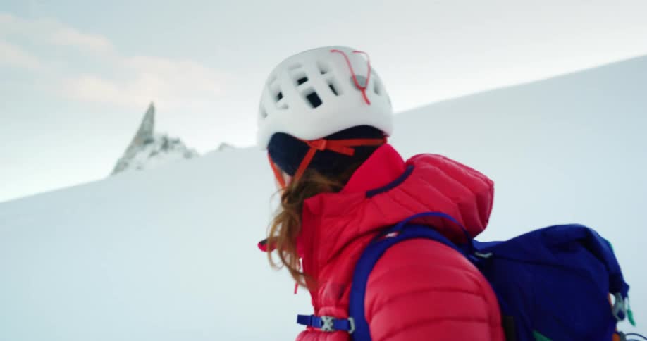 Two people are climbing a snow covered mountain