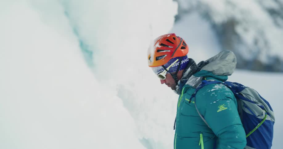 Man standing at base of frozen slope swings his arms