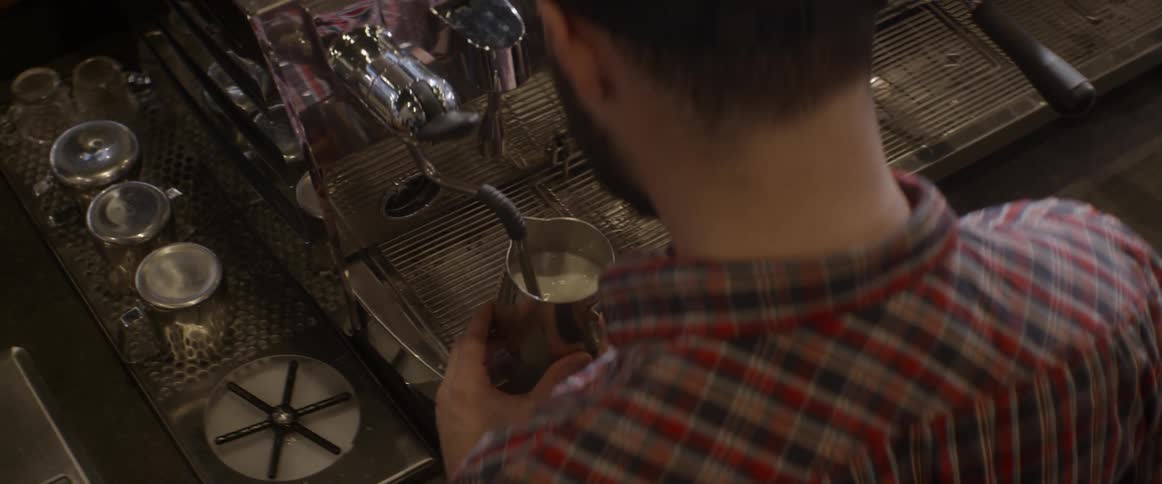 A man is steaming milk at a professional grade machine