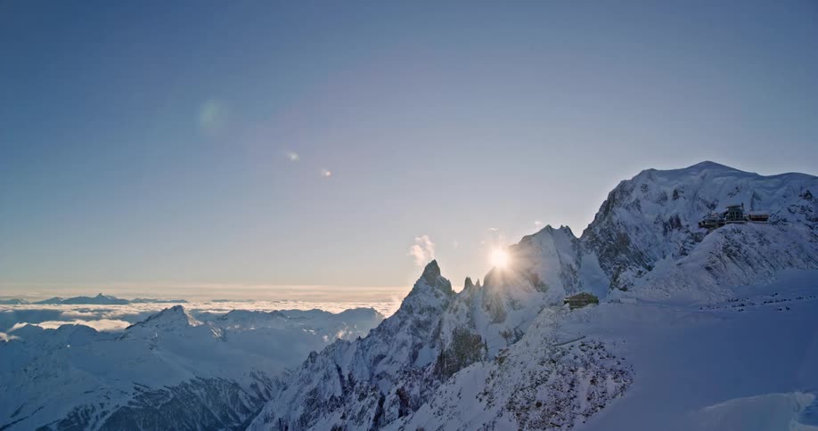 Sun shining over snowy mountains from above